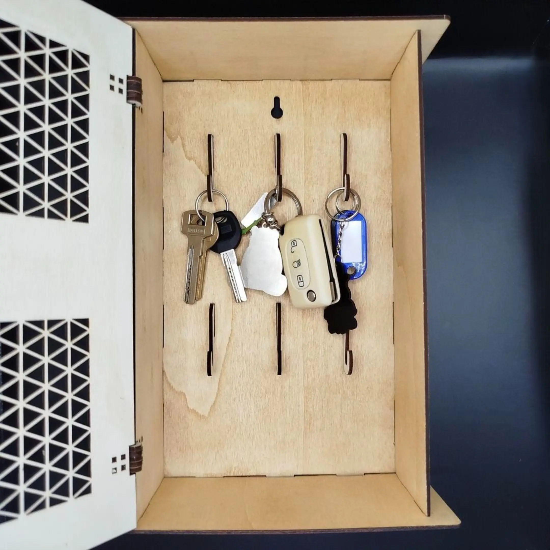 Open wooden key cabinet with keys hanging inside