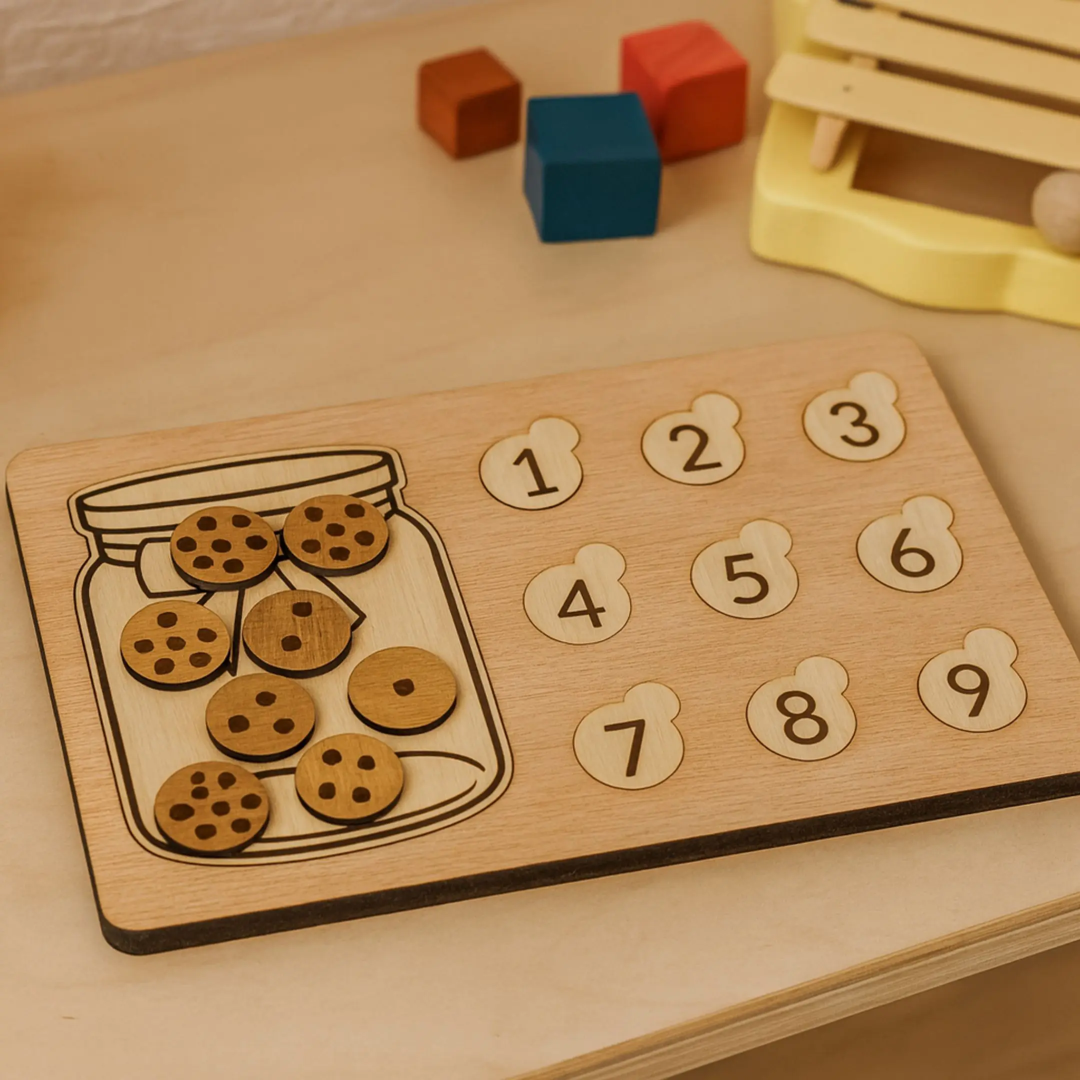 Wooden counting board with chocolate chip cookie pieces and number slots, placed on a children's play table.