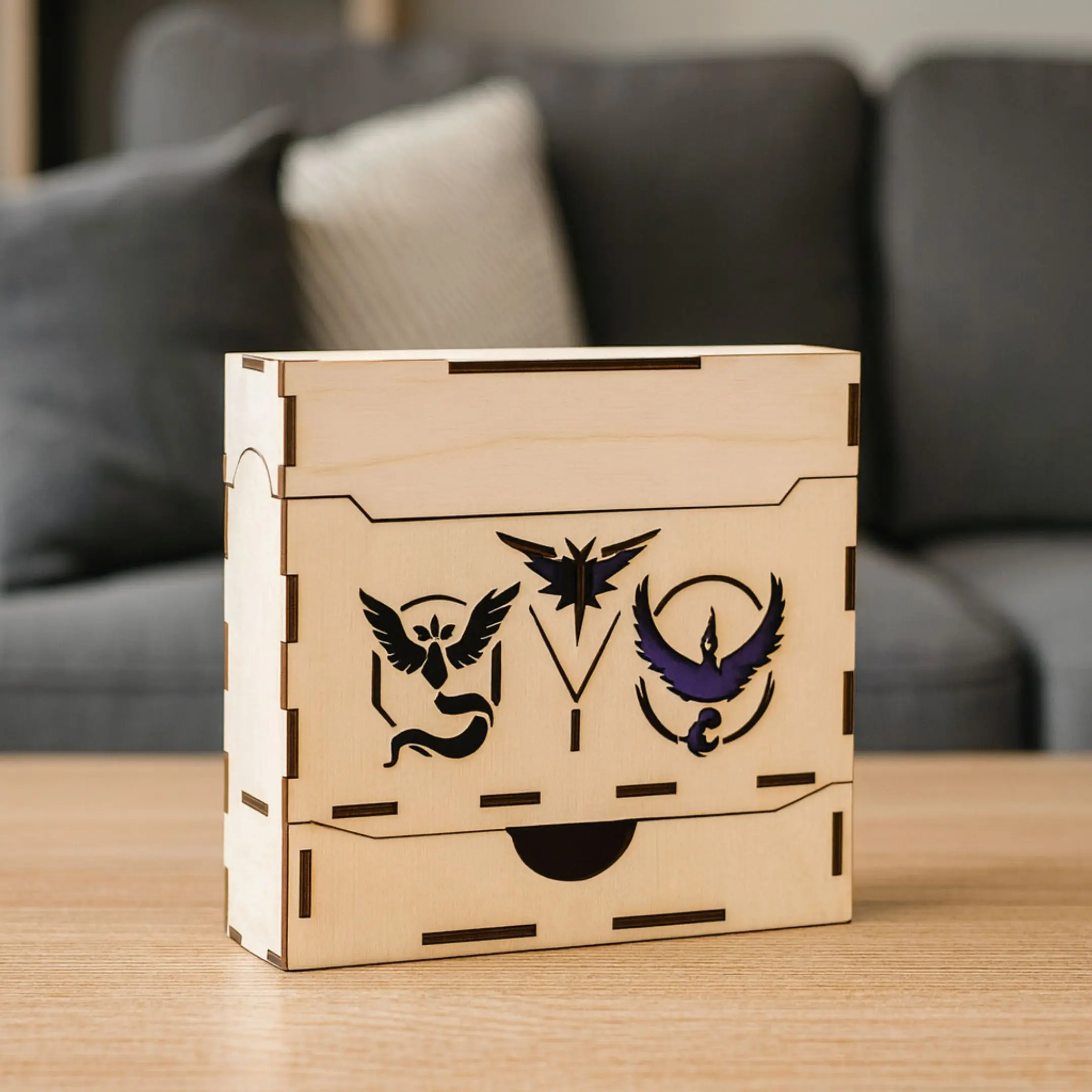Laser cut wooden deck box with team symbols, standing on a table in a room.