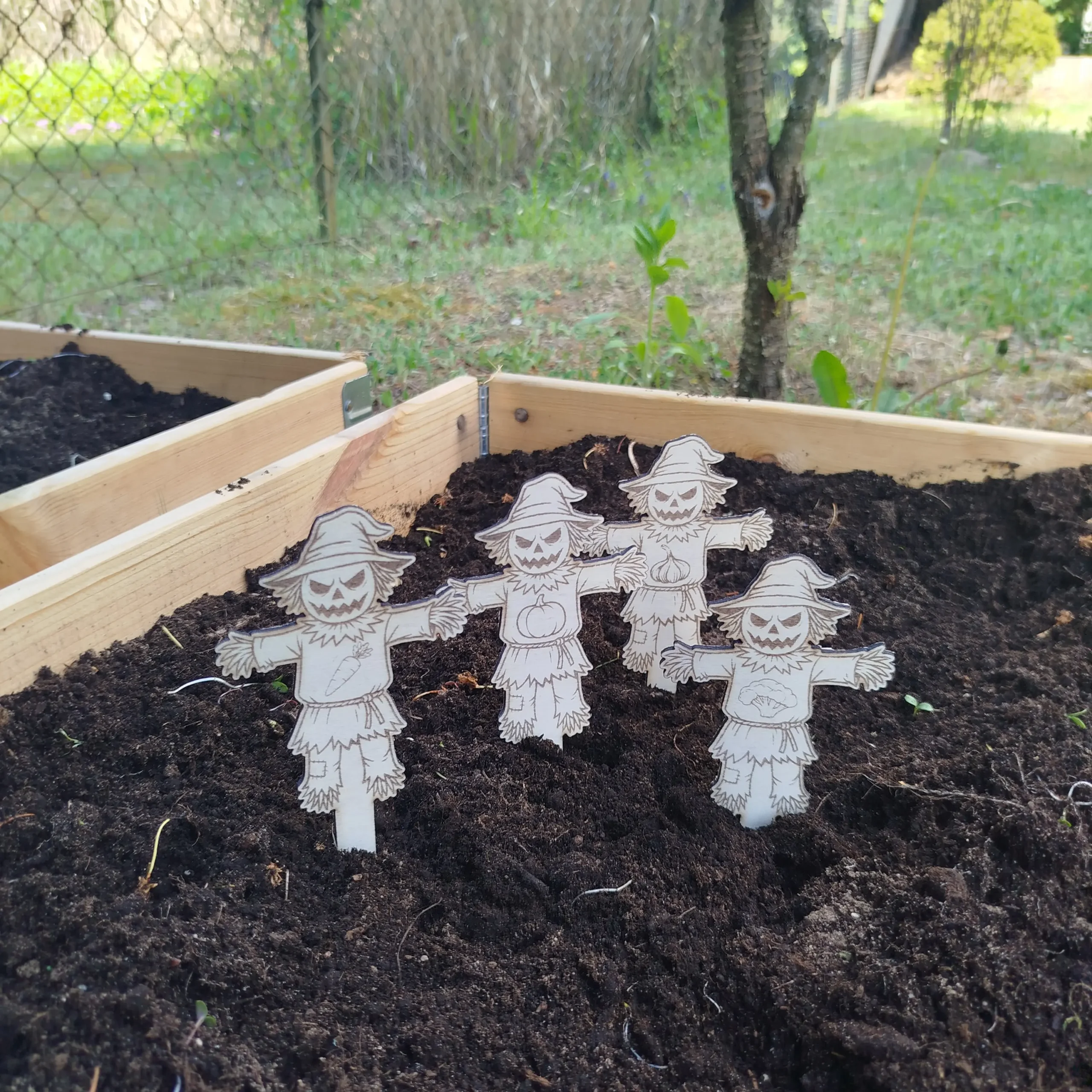 Side view of scarecrow-shaped laser cut plant markers with engraved vegetable symbols