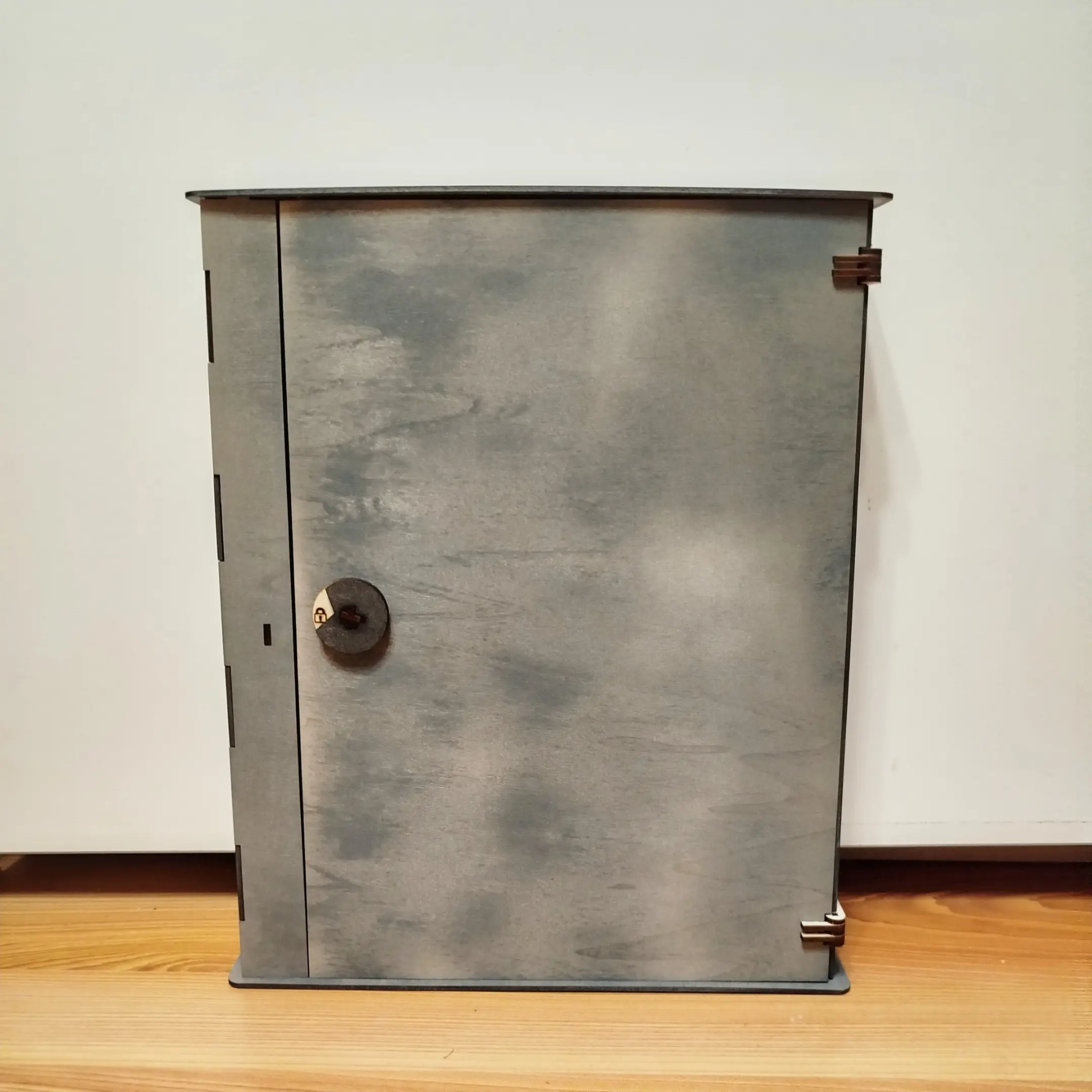 Closed wooden key cabinet with visible metal locking mechanism.