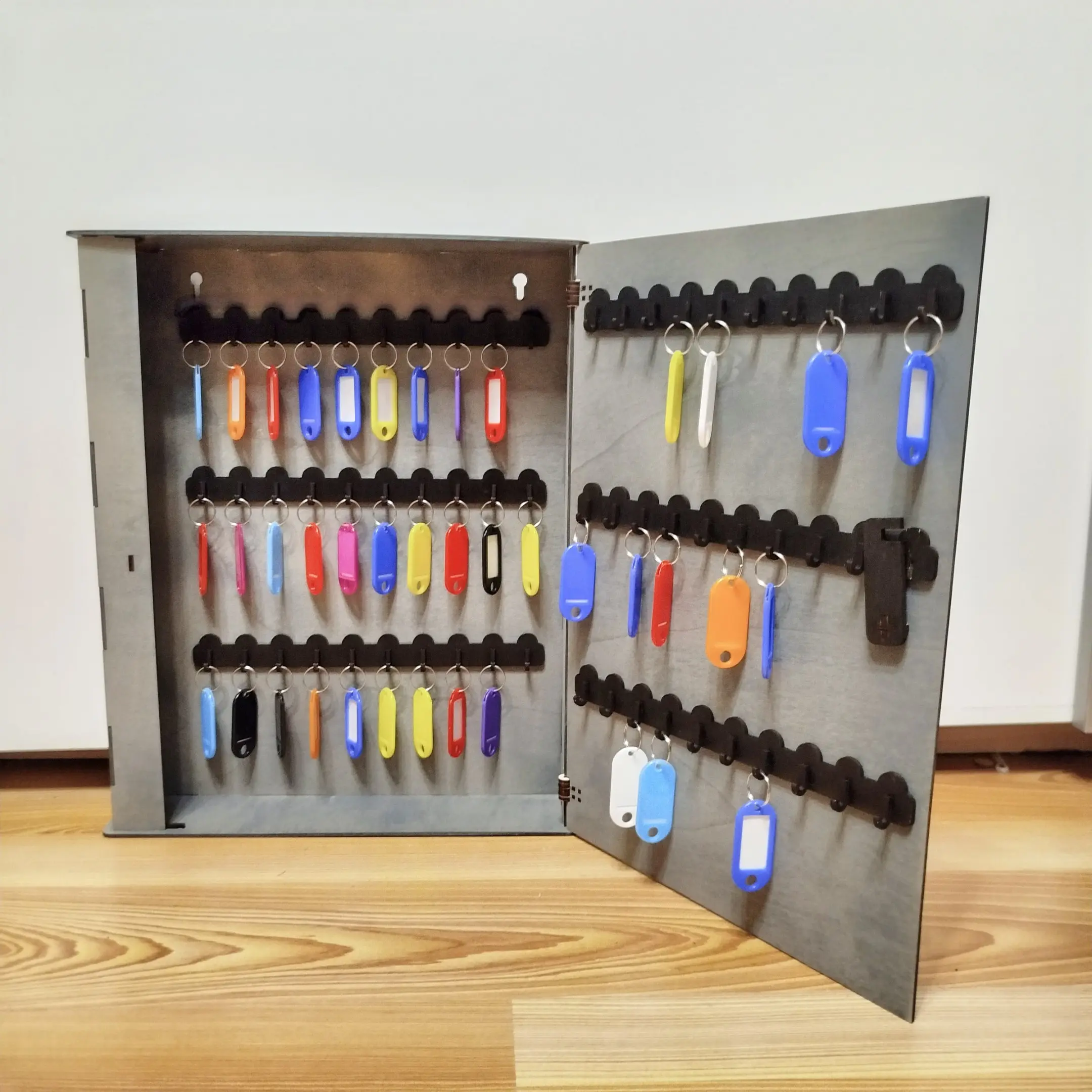 Open wooden key cabinet with multiple keys organized inside.