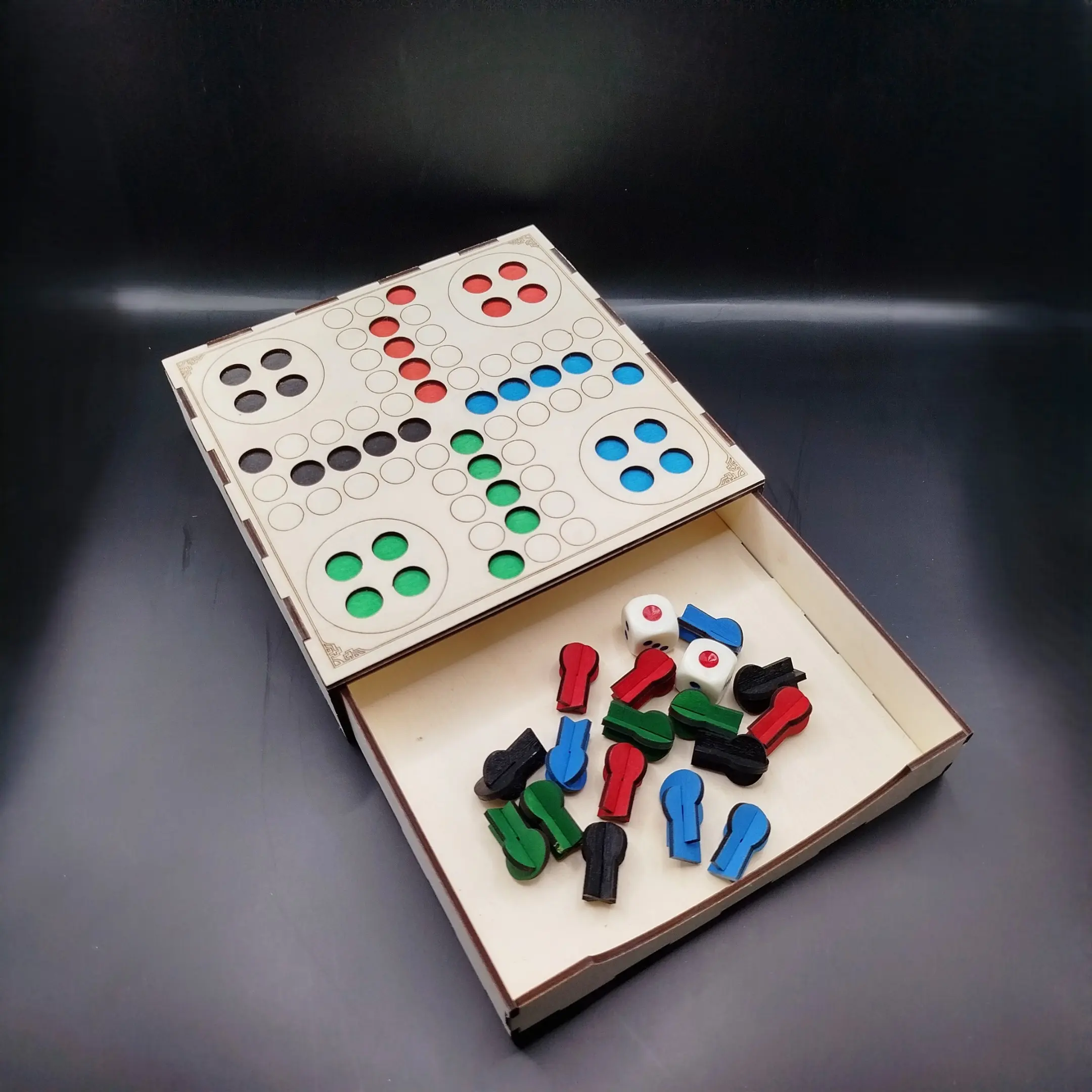 Laser cut Ludo board game with open storage drawer showing colorful playing pieces.